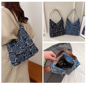 Detailed view of floral embroidery and interior of denim tote bag with brown strap