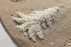 Detailed close-up of cream knit tree skirt with soft 3D plush white fir tree pattern