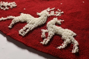 Detail of red knitted Christmas tree skirt with white reindeer and snowflake patterns