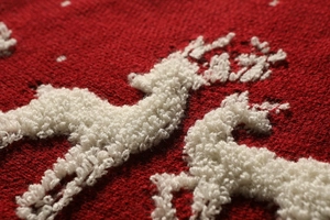 Detailed macro shot of red knitted Christmas tree skirt with white plush reindeer embroidery