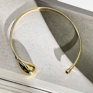 Close-up of minimalist gold teardrop choker necklace featuring asymmetric metal drop