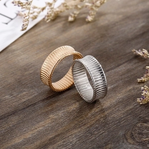 Textured 18K gold and silver striped stainless steel rings on a rustic wood background