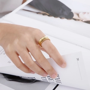 Detail of 18K gold-plated wide striped ring with textured surface on a hand