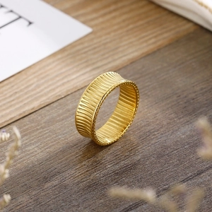 Macro detail of gold striped band ring with beaded edges on a rustic wooden texture