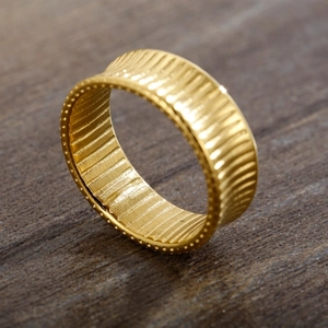 Macro detail of 18K gold plated striped ring with beaded edges on a wood surface