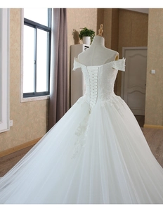 Dettaglio dell'abito da sposa in pizzo bianco con lacci incrociati sul corpetto