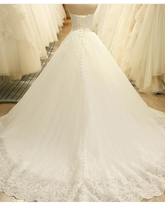 Dettagli del retro di un abito da sposa avorio con allacciatura e un lungo strascico