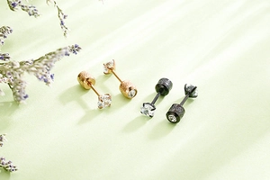 Detail of rose gold and black stud earrings with four-prong cubic zirconia and screw backs