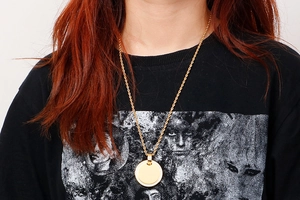 Detailed view of a gold-plated titanium steel round pendant necklace on a model