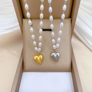 Gold and silver heart necklaces with white pearls in a jewelry display box