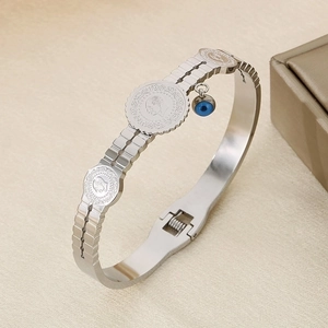 Detail of silver steel bracelet with coin reliefs, evil eye charm and watchband texture