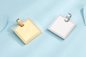 Detailed view of gold and silver square pendants with CNC-set zircon on light blue background