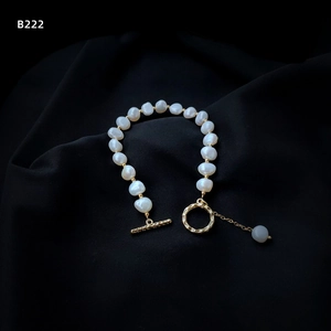 Macro detail of natural Baroque pearl bracelet with golden OT clasp on black satin