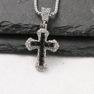 Close-up of a silver cross pendant with black square gemstones and micro-pave crystals