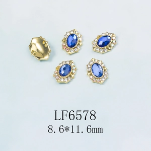 Détail de strass bleus ovales pour ongles avec base dorée et petits cristaux brillants