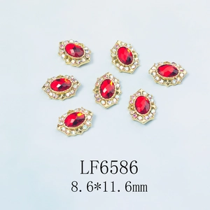 Détail du bijou d'ongle LF6586 avec gemme rouge ovale et contour doré serti de diamants