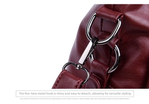 Macro detail of glossy silver metal hook and wine red leather strap on the shoulder bag