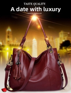 Detail of dark red leather handbag with tassel charm and polished metal hardware
