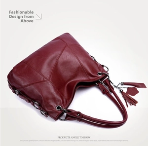 Overhead view of burgundy leather tote bag featuring X-shaped stitching and fringe tassel