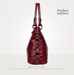 Detailed side view showing textured burgundy leather handbag with metal ring accents
