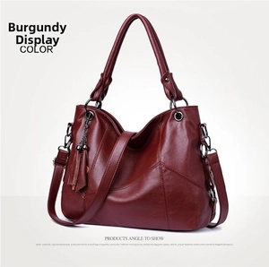 Detail of wine red large capacity faux leather bag with matching tassel and silver hardware