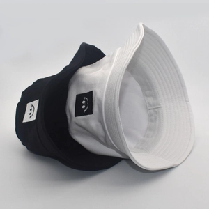Detailed view of black and white cotton bucket hats featuring a minimalist smile patch