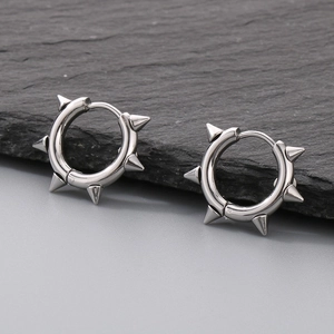 Close-up of silver stainless steel hoop earrings with punk rivets on a dark stone
