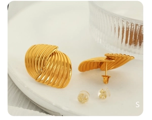 Macro detail of gold striped textured earrings with metal and silicone backings