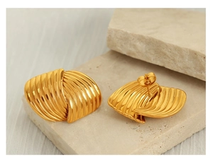 Detailed view of gold fan-shaped textured earrings displayed on natural white stones