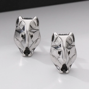 Close-up of vintage titanium steel wolf head earrings with detailed metallic textures