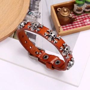 Close-up of a brown leather punk bracelet featuring metal skulls and adjustable buckle