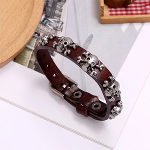 Detail of brown leather punk bracelet with silver skull charms and buckle closure