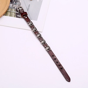 Detail view of dark brown leather punk bracelet with silver skull metal studs and buckle