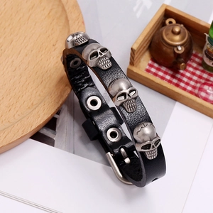 Close-up of punk style black cowhide leather bracelet with silver skull metal charms