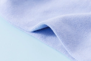 Detailed close-up of light blue combed cotton fabric showing soft knitted texture and weave