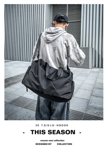 Modern black duffel bag for gym or travel, styled in an urban outdoor setting