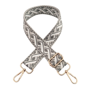 Detail of grey and white geometric woven bag strap with adjustable gold metal buckle
