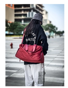 Close-up of a red waterproof sports bag with adjustable shoulder straps in urban setting