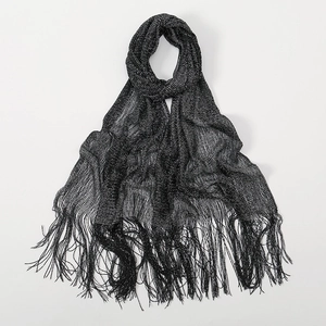 Detailed view of dark grey metallic yarn scarf featuring long fringe tassels and shimmer