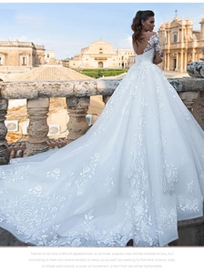 Detail of the open back V-neck and delicate lace embroidery on long sleeve wedding gown