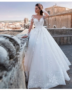 Close-up of elegant long sleeve bridal gown with intricate floral lace and illusion neckline