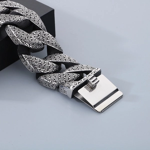 Detail of silver stainless steel Cuban chain bracelet with scale-like texture and clasp