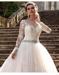 Détails de robe de mariée blanche en dentelle avec manches longues et ceinture perlée