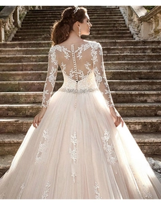 Détail d'une robe de mariée avec manches longues en dentelle et dos transparent à boutons