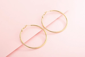 Gros plan détaillé des boucles d'oreilles créoles dorées avec fermoir classique
