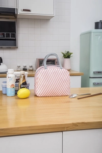 Detailed view of striped lunch bag with gray woven handles in a bright kitchen