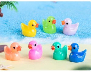 Miniature resin duck figurines in seven colors arranged on a beach-themed scenery