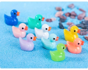 Group of nine colorful miniature resin ducks on blue sand for micro landscape decor
