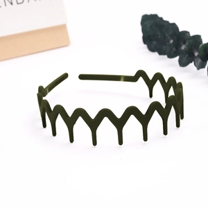 Close-up of a matte dark green wavy headband with anti-slip teeth on a clean white base