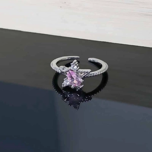 Close-up of star zircon ring with pink marquise gemstone on a reflective black surface